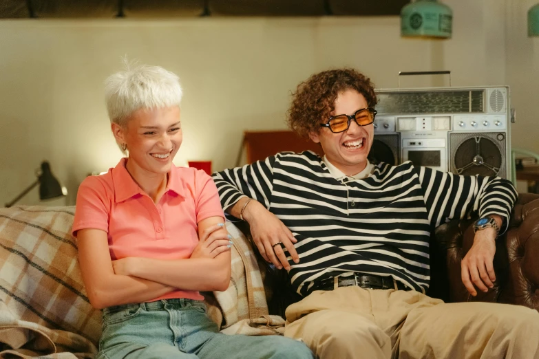 a couple of people sitting on top of a couch, pexels, serial art, wears glasses, short curly blonde haired girl, amused, charli bowater and artgeem