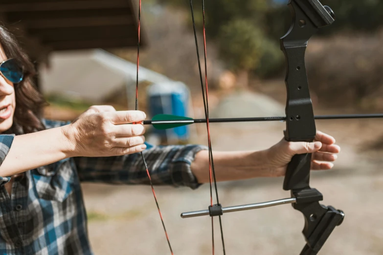 a woman holding a bow and aiming an arrow, by Joe Bowler, pexels contest winner, fan favorite, hands pressed together in bow, rectangle, outside