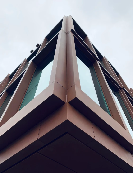 a tall brown building with lots of windows, inspired by David Chipperfield, unsplash, wall corner, copper, low quality photo, thumbnail