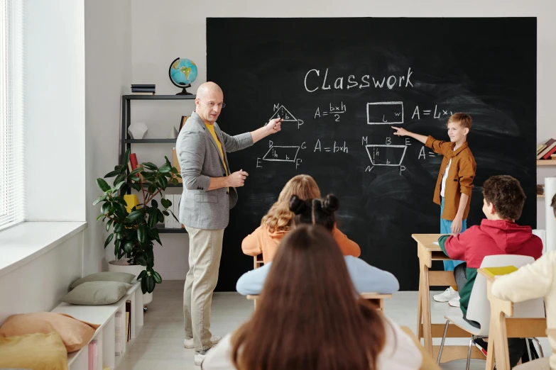 a man standing in front of a blackboard in a classroom, trending on pexels, worksafe. instagram photo, ayne haag, back to school comedy, a group of people