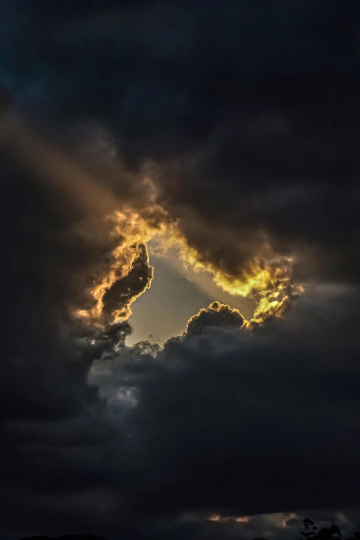 the sun is shining through the clouds, a picture, by Robert Storm Petersen, pexels contest winner, cloud in the shape of a dragon, surreal black and yellow, centered in the frame, night clouds