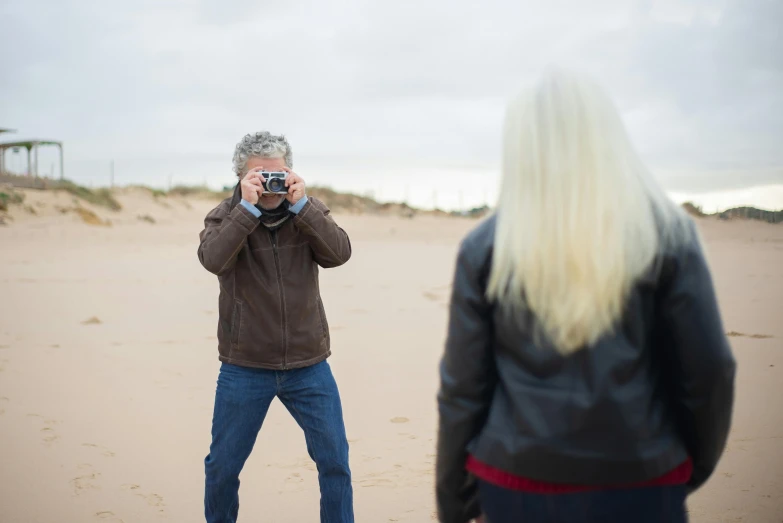 a man taking a picture of a woman on the beach, a picture, inspired by Storm Thorgerson, unsplash, mid portrait, medium format, looking furious, adult