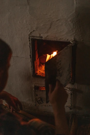 a man that is sitting in front of a fire, arte povera, glowing heating coils, india, oven, close look