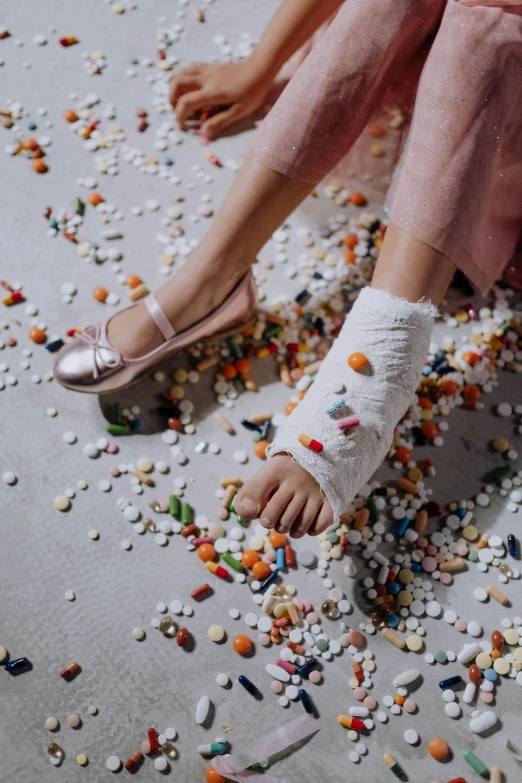 a woman sitting on top of a bed covered in pills, an album cover, by Elsa Bleda, trending on pexels, hyperrealism, pink shoes, brick debris, detail shot, snacks