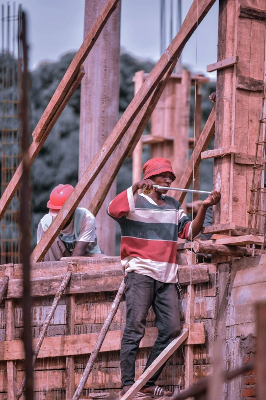 a group of men standing on top of a wooden structure, inspired by Afewerk Tekle, pexels contest winner, constructivism, pink concrete, working hard, 1970s philippines, closeup photograph