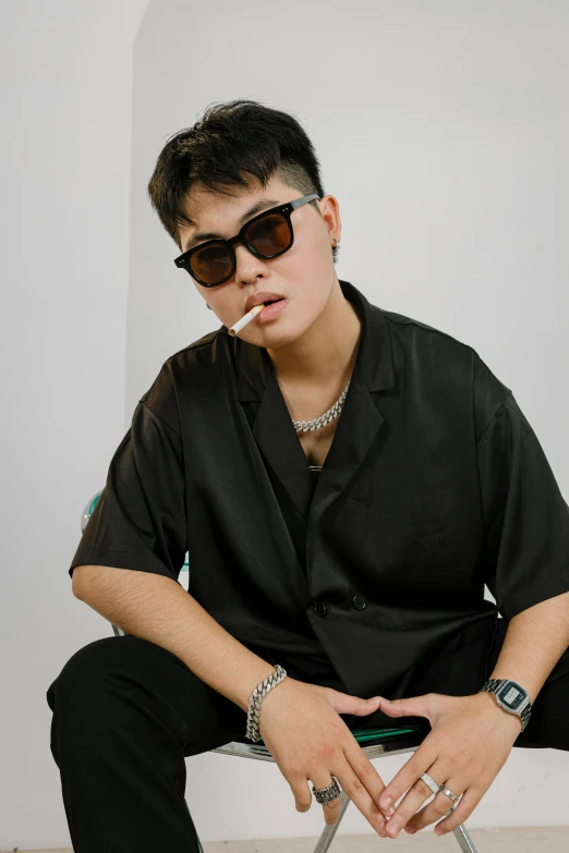 a man sitting on a chair smoking a cigarette, an album cover, inspired by Ion Andreescu, trending on pexels, half man half asian black bull, short platinum hair tomboy, shades, shirt