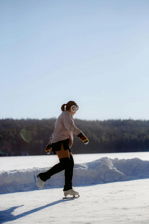 a woman riding a skateboard across a snow covered field, inspired by Eero Järnefelt, happening, walkable, near a lake, new hampshire, wearing sunglasses and a cap