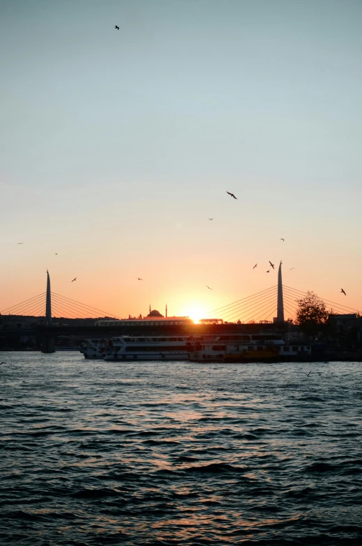 the sun is setting over a body of water, a picture, inspired by Nadim Karam, hurufiyya, istanbul, medium-shot, multiple stories, ships