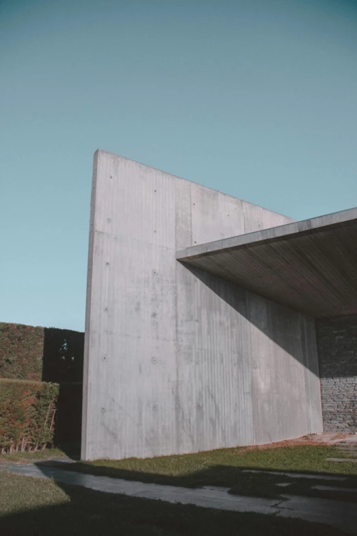 a concrete building sitting on top of a lush green hillside, an album cover, inspired by Tadao Ando, unsplash, brutalism, wall structure, chile, angular minimalism, cementary