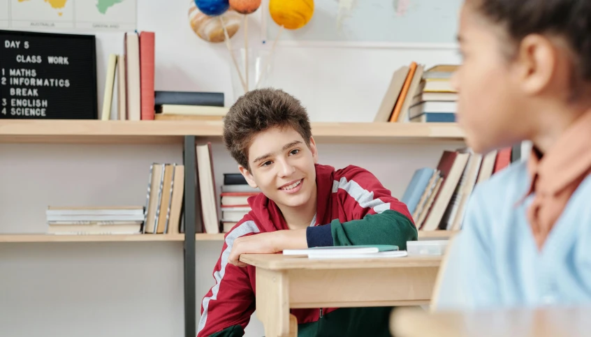 a boy and a girl sitting at a table, trending on pexels, danube school, smiling spartan, looking to his side, teenage boy, in small room