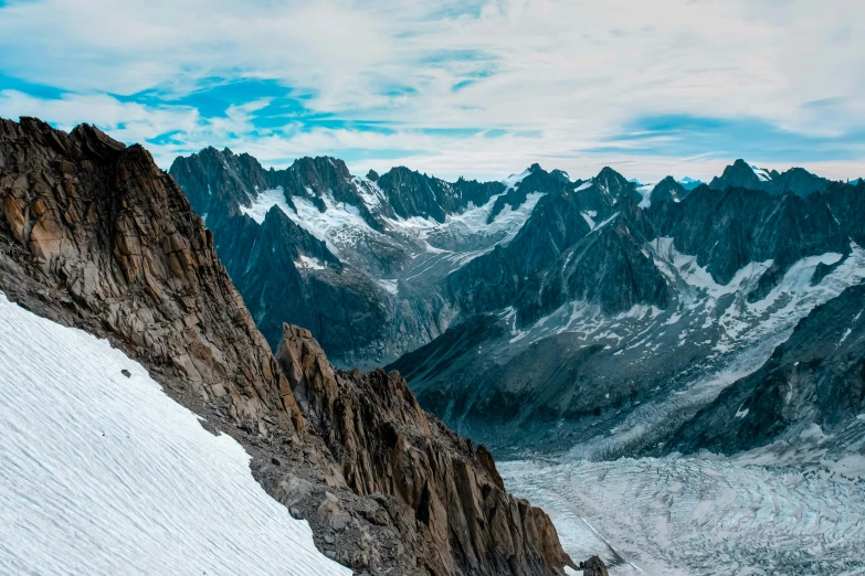 a man standing on top of a snow covered mountain, pexels contest winner, les nabis, shades of blue and grey, “ aerial view of a mountain, brown, tall stone spires