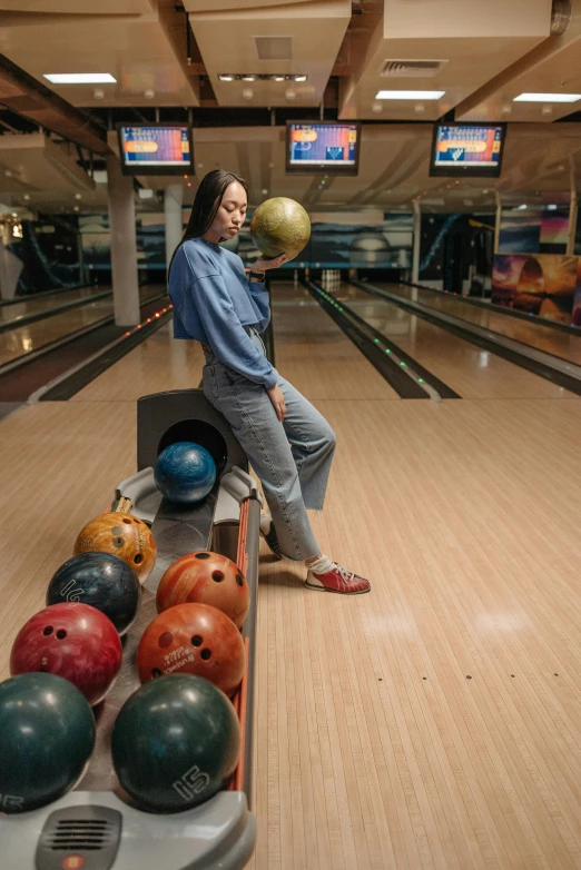 a woman standing next to a row of bowling balls, darren quach, casual pose, portait image, high quality image