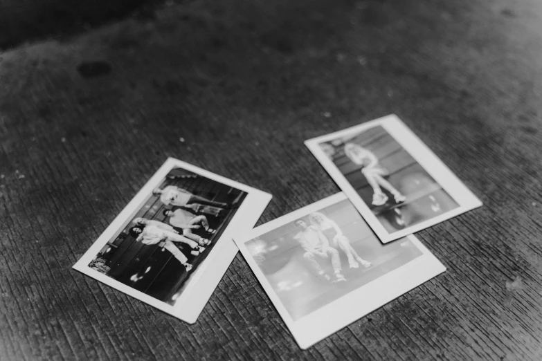 a couple of polaroids sitting on top of a table, a black and white photo, rollerskaters, photographic print, high details photo