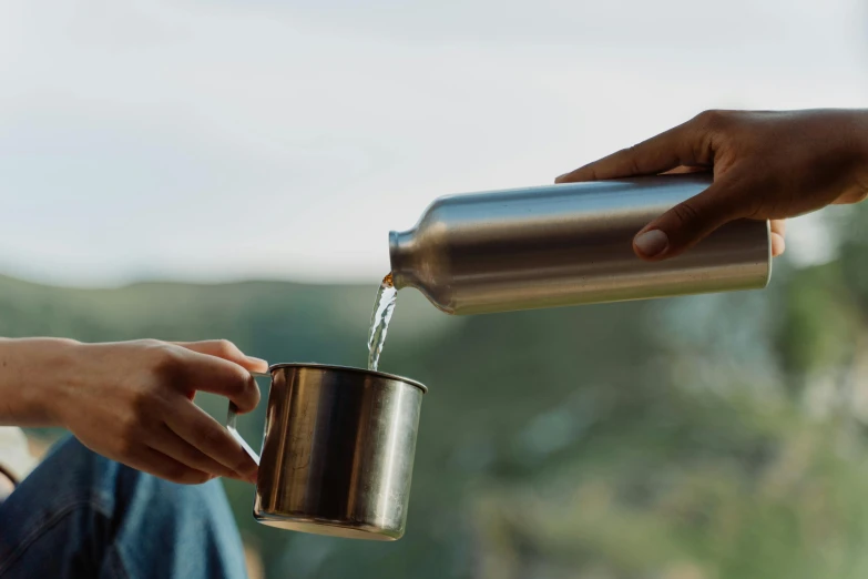 a person is pouring water into a cup, by Will Ellis, unsplash, made of brushed steel, picnic, manuka, dwell