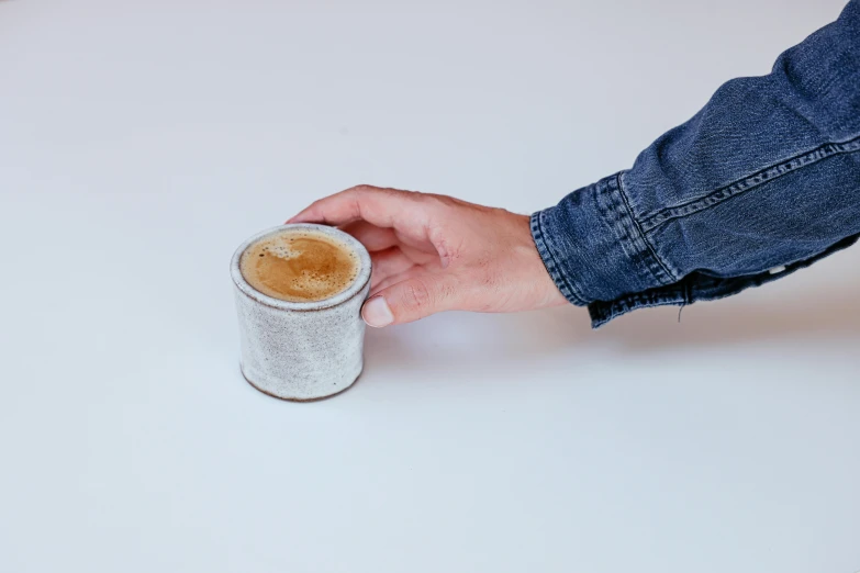 a person holding a cup of coffee on a table, inspired by Hendrik Gerritsz Pot, textured base ; product photos, white background and fill, enamel, vanilla