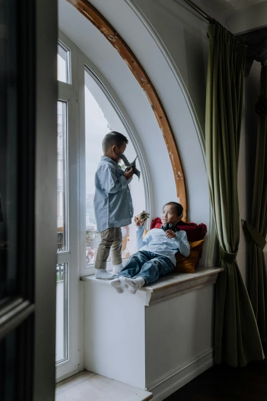 a couple of kids sitting on top of a window sill, by Jan Tengnagel, pexels contest winner, hotel room, arched ceiling, kids playing, in their noble mansion