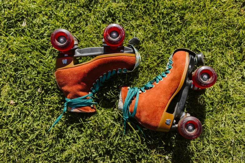 a pair of roller skates sitting on top of a lush green field, red and orange color scheme, corduroy, orange and turquoise, straps