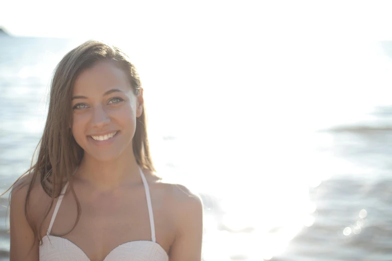 a beautiful young woman standing in front of a body of water, bright smile, avatar image, sunfaded, profile image