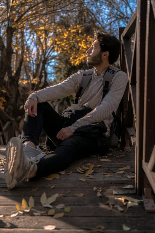 a man sitting on top of a wooden bridge, by Niko Henrichon, pexels contest winner, handsome male, sitting on the ground, avatar image, mid fall