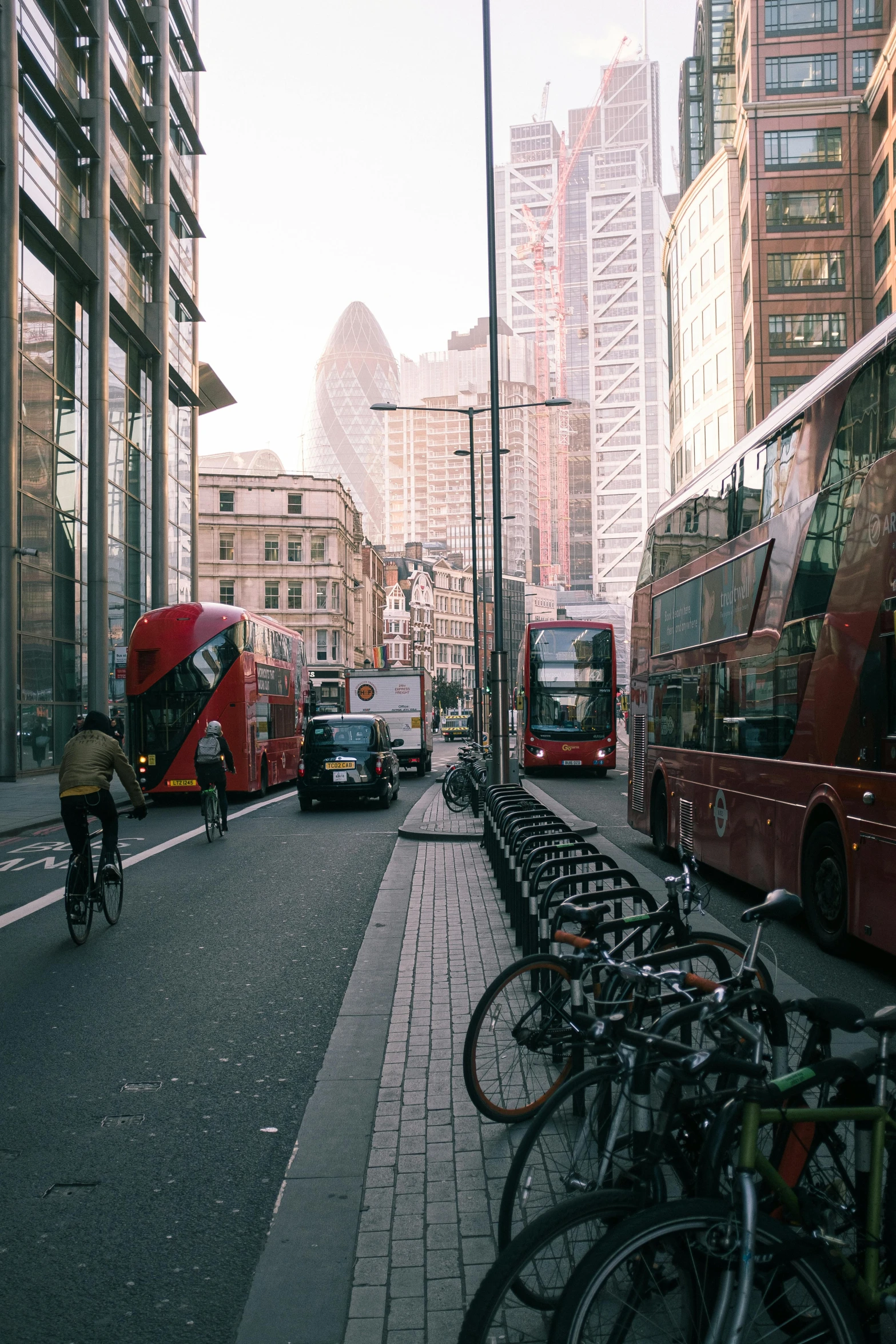 a red double decker bus driving down a city street, by Adam Rex, pexels contest winner, modernism, bicycles, high rises, square, broken down