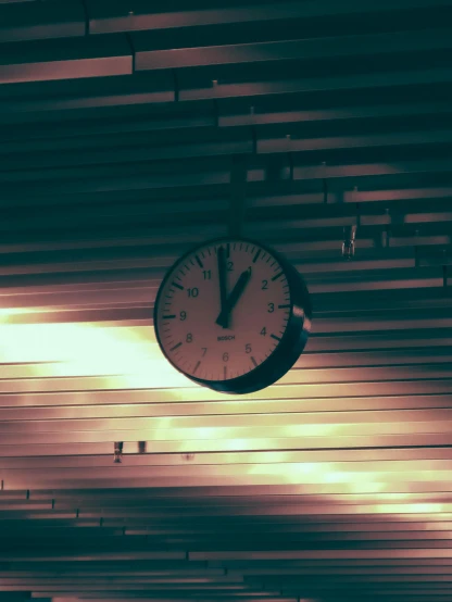 a clock hanging from the ceiling of a train station, a picture, inspired by Elsa Bleda, unsplash, postminimalism, ( ( ( synthwave ) ) ), profile image, taken in the late 2000s, low quality grainy