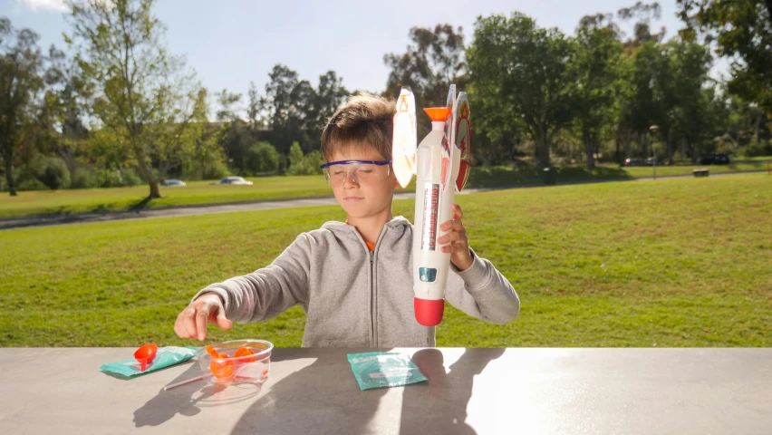 a young boy is playing with a toy rocket, by Rube Goldberg, pexels contest winner, pi-slices and kidmograph, jet turbine, scenic full shot, official product photo