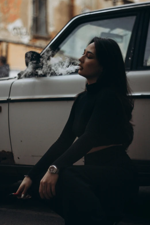 a woman sitting on the ground next to a car, inspired by Elsa Bleda, trending on pexels, renaissance, smoking a blunt, profile image, female with long black hair, chemistry
