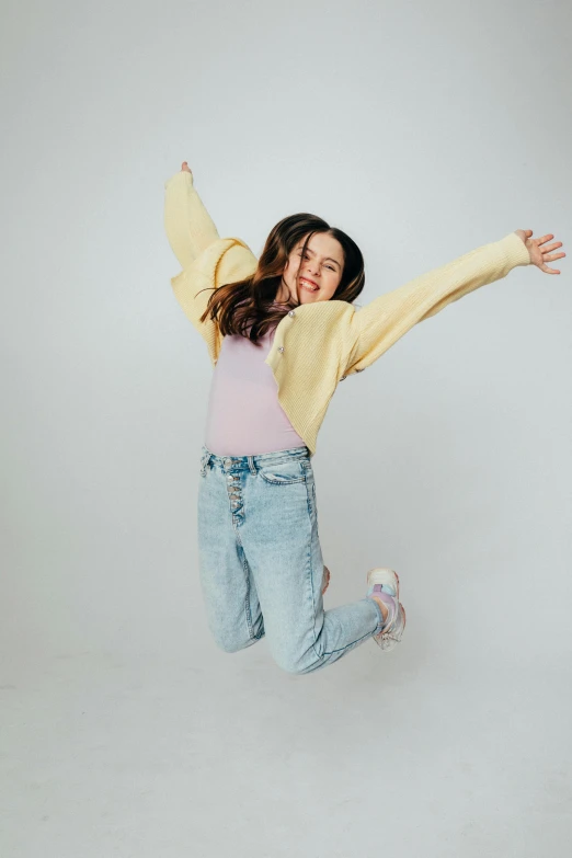 a little girl that is jumping in the air, an album cover, pexels, miranda cosgrove, wearing a yellow hoodie, pastel clothing, 15081959 21121991 01012000 4k