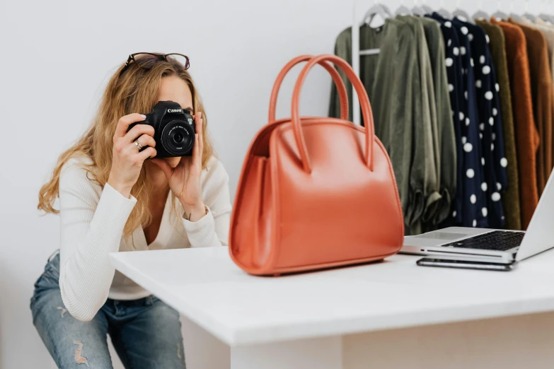 a woman taking a picture of herself with a camera, by Nicolette Macnamara, bag, ecommerce photograph, small, customers