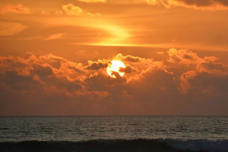 a person riding a surfboard on top of a wave, by Robbie Trevino, pexels contest winner, romanticism, orange sun set, sri lanka, view of the ocean, sunset in the clouds