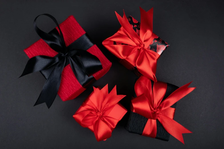 three red gift boxes with black bows on a black background, a still life, by Julia Pishtar, pexels contest winner, hurufiyya, wrapped in black, overview, small, black