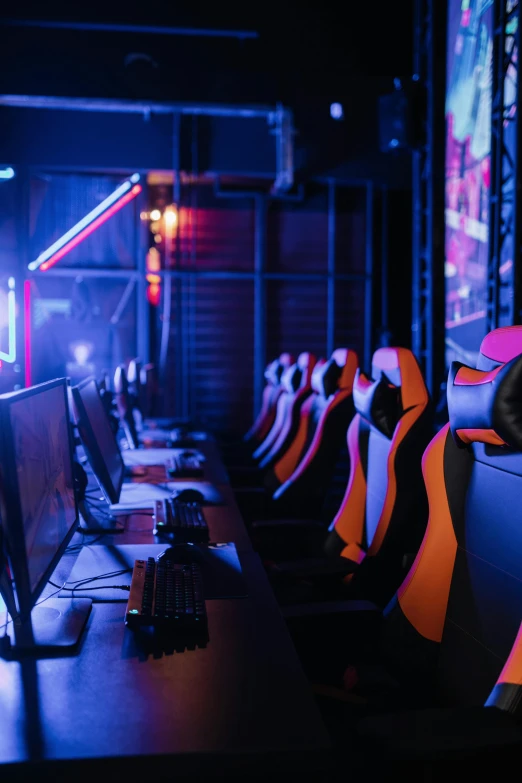 a row of computer monitors sitting on top of a desk, softair arena landscape, orange and red lighting, comfy chairs, thumbnail