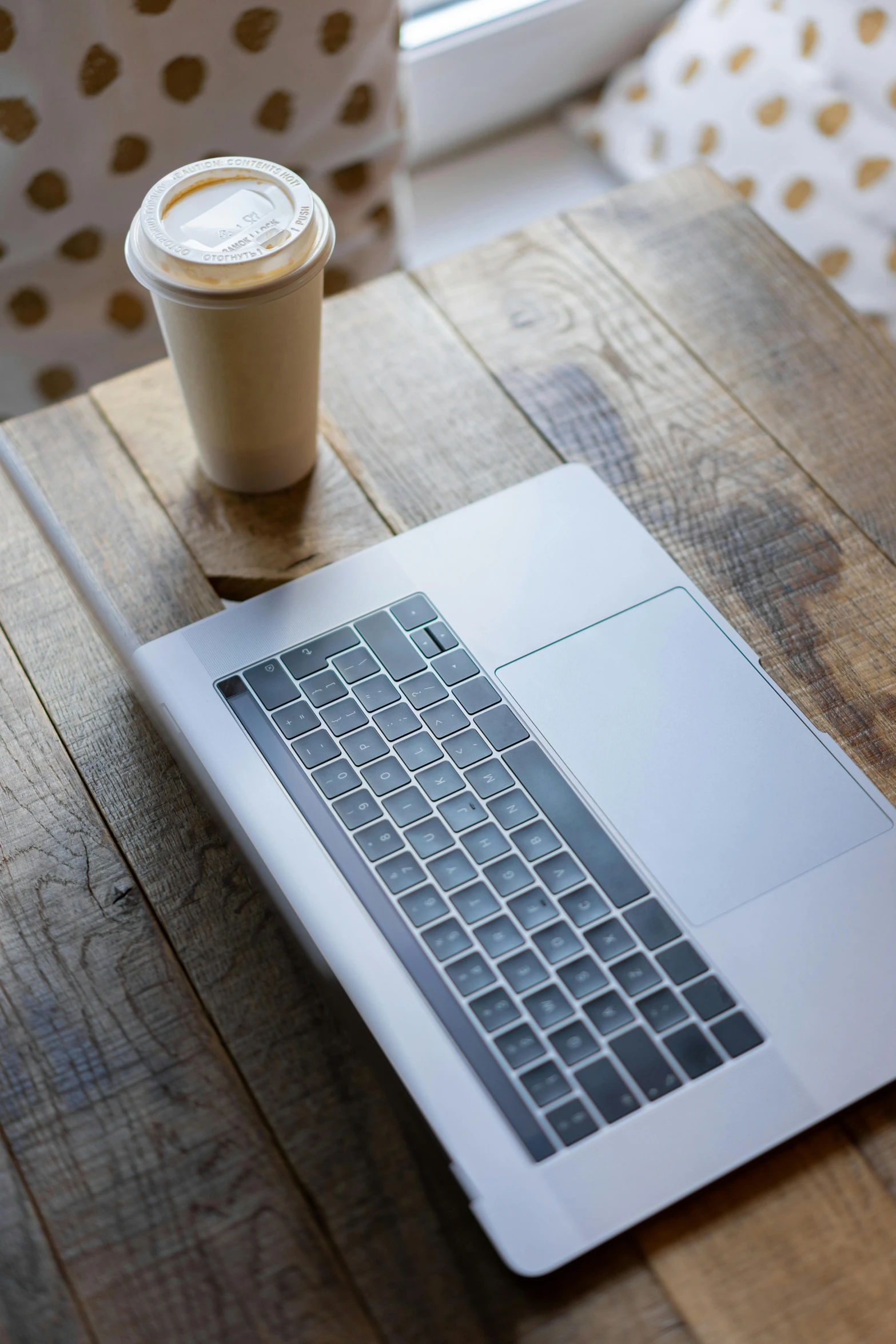 a laptop computer sitting on top of a wooden table, by Carey Morris, pexels, iced latte, promo image, bottom angle, gold