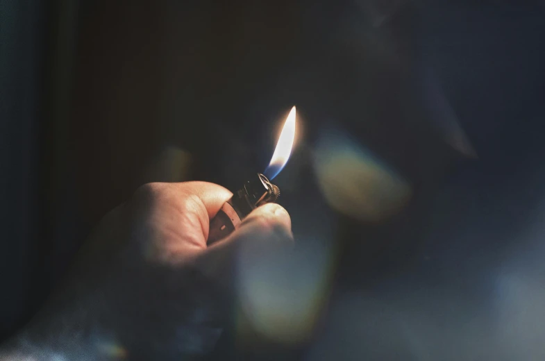 a person holding a lighter in their hand, an album cover, inspired by Elsa Bleda, trending on pexels, light and space, chiaroscuro soft lighting, tiny firespitter, candle wax, instagram post