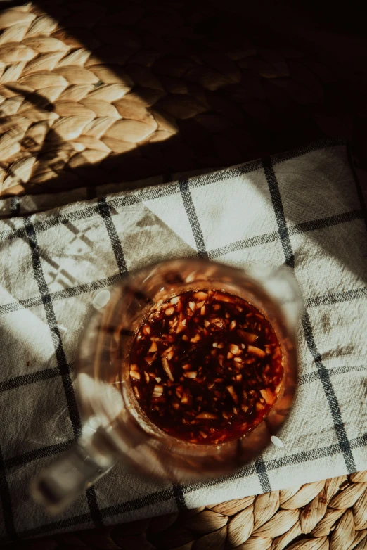 a glass of tea sitting on top of a table, pexels contest winner, visual art, leaves and simple cloth, sun puddle, holding hot sauce, dried petals