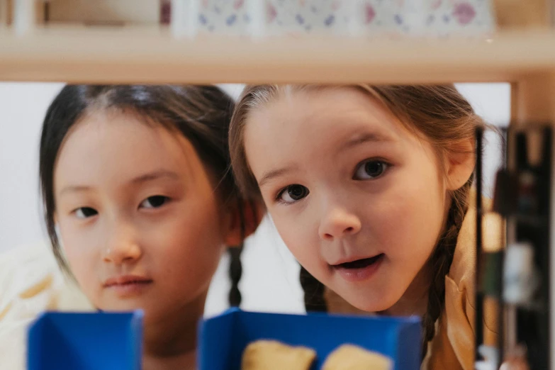 a couple of young girls standing next to each other, by Lee Loughridge, pexels contest winner, people inside eating meals, middle close up, looking at the treasure box, darren quach