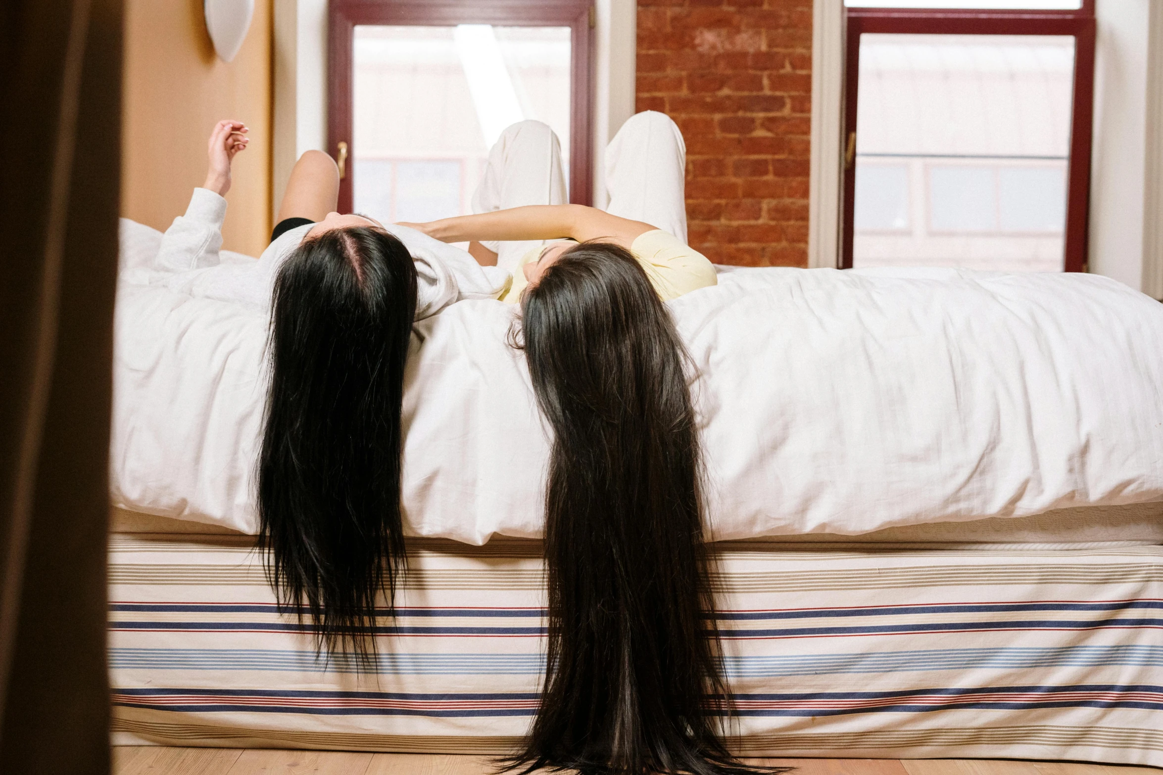 a woman laying on a bed with long black hair, trending on pexels, hurufiyya, siamese twins, facing away, sisters, thinning hair