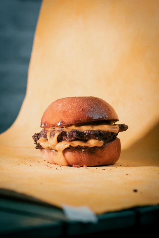 a hamburger sitting on top of a piece of paper, caramel. rugged, chocolate. rugged, melted cheese, woodfired