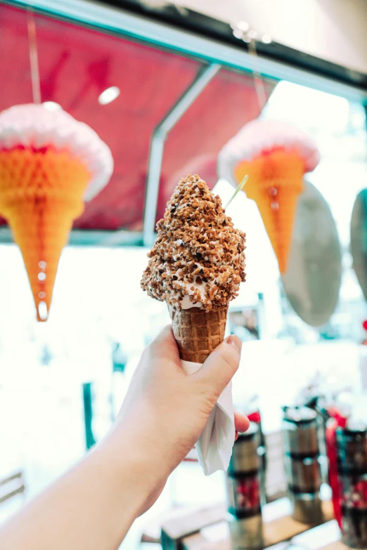 a person holding an ice cream cone in their hand, sea of parfait, displayed, brown, seattle