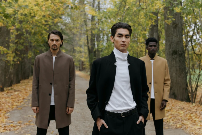 a group of men standing next to each other on a road, an album cover, by Emma Andijewska, pexels contest winner, bauhaus, grey turtleneck coat, smooth models, standing in a forest, 3-piece-suit