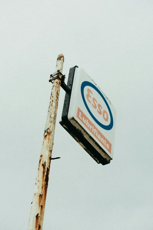 a close up of a sign on a pole, an album cover, unsplash, abandoned gas station, scotland, icon, 50 years old