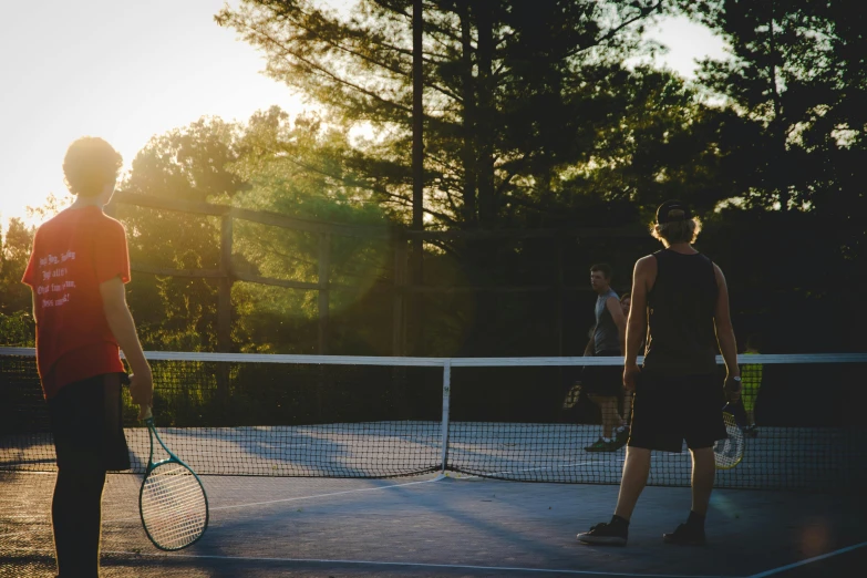 a couple of men standing on top of a tennis court, by Julia Pishtar, unsplash contest winner, late afternoon sun, at the park, miranda meeks, dylan kowalsk