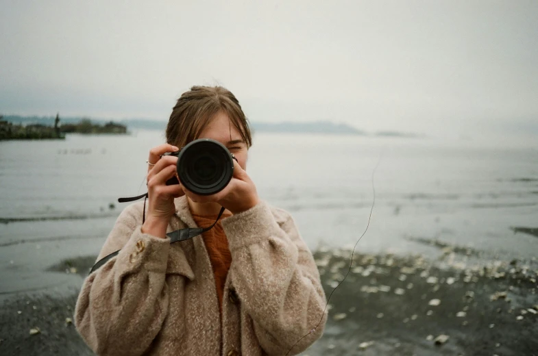 a woman taking a picture with a camera, a picture, by Anna Boch, pexels contest winner, telephoto long distance shot, looking directly at the camera, round format, carson ellis
