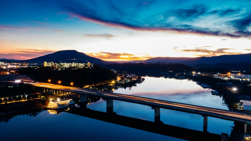 a bridge over a large body of water, by Ben Thompson, pexels contest winner, twilight ; wide shot, birdseye view, thumbnail, distant mountains lights photo