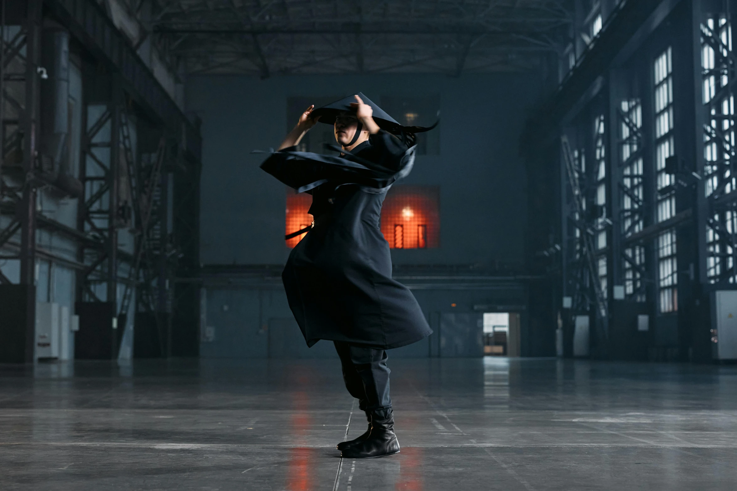 a woman in a black coat is dancing, inspired by Ma Quan, pexels contest winner, visual art, ninja outfit, in a warehouse, man standing in defensive pose, **cinematic