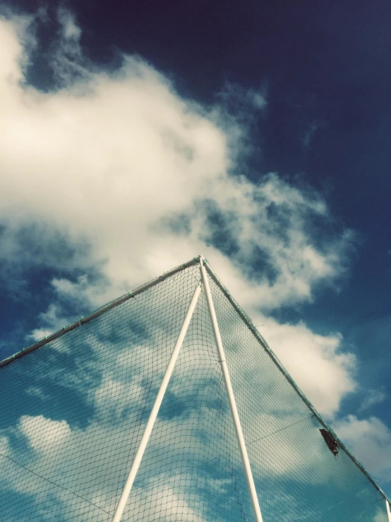 a tennis racket sitting on top of a tennis court, an album cover, by Niko Henrichon, unsplash, aestheticism, cloud in the sky, triangle, netting, looking upwards