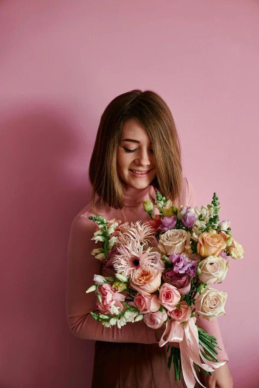 a woman holding a bouquet of flowers against a pink wall, smiling sweetly, with lots of details, looking off to the side, on grey background