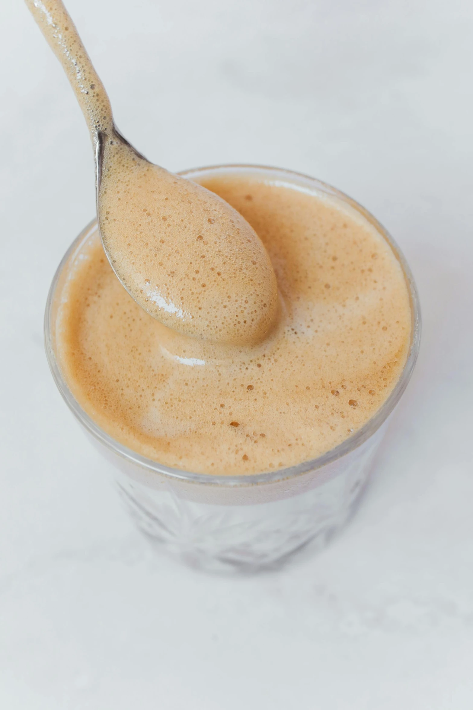 a spoon that is sitting in a cup, iced latte, zoomed out, thumbnail, no cropping