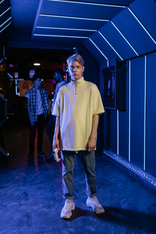 a man in a yellow shirt holding a tennis racquet, an album cover, inspired by Nikolaj Abraham Abildgaard, featured on reddit, in a nightclub, cinematic full body shot, wearing a baggy, wearing polo shirt