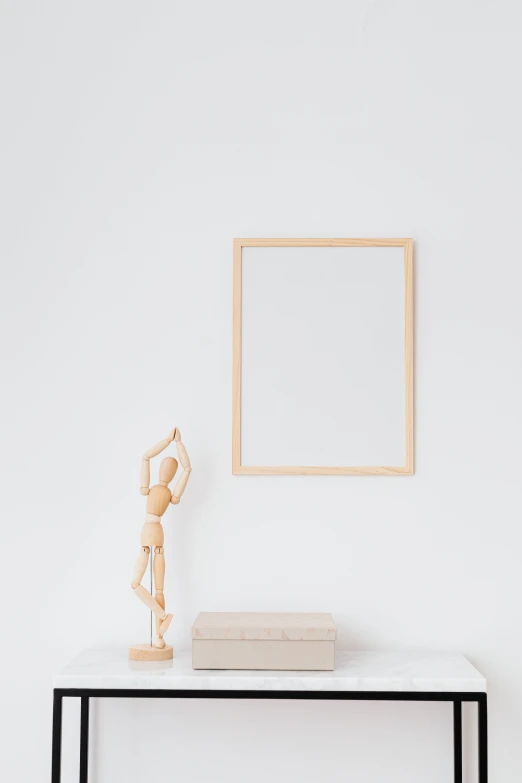 a wooden statue sitting on top of a table next to a white wall, a minimalist painting, trending on unsplash, square pictureframes, mirror background, high-quality photo, pointè pose